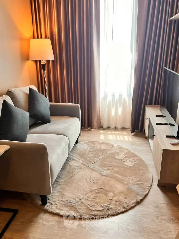 Cozy living room with elegant decor, featuring a plush sofa, stylish lamp, and natural light from large window.