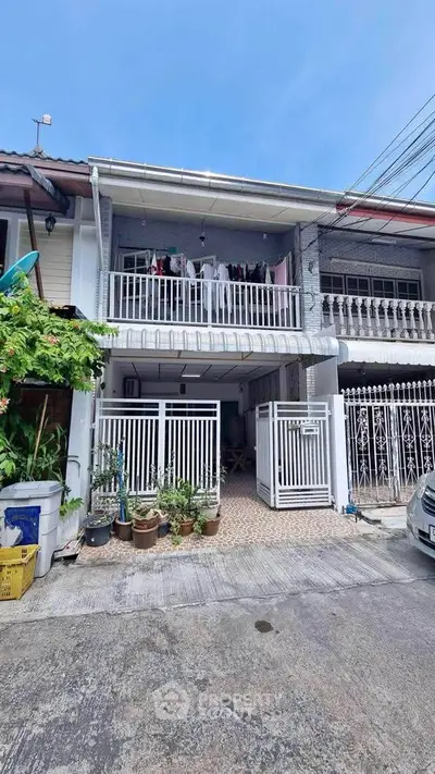 Charming two-story townhouse with balcony and gated entrance in a serene neighborhood.