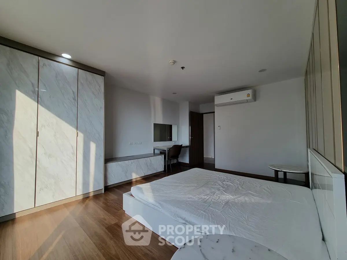 Spacious bedroom with modern design and ample natural light, featuring a built-in wardrobe and air conditioning.