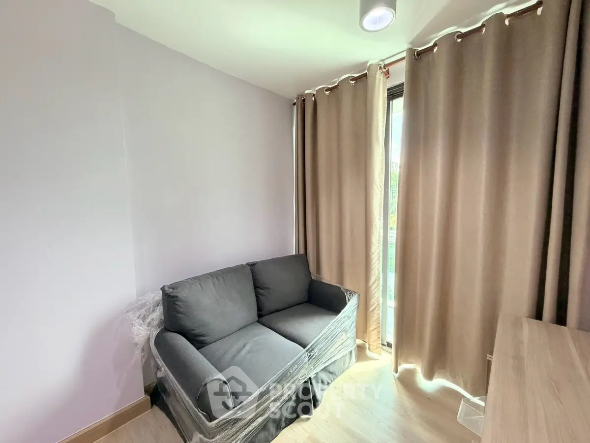 Cozy small living room with a compact sofa and large window with curtains, perfect for relaxation.