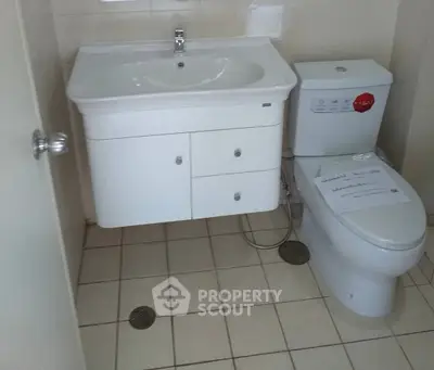 Compact bathroom with modern sink and toilet, tiled floor, ideal for small spaces.