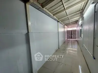 Spacious corridor with tiled flooring and natural light, ideal for storage or utility use.