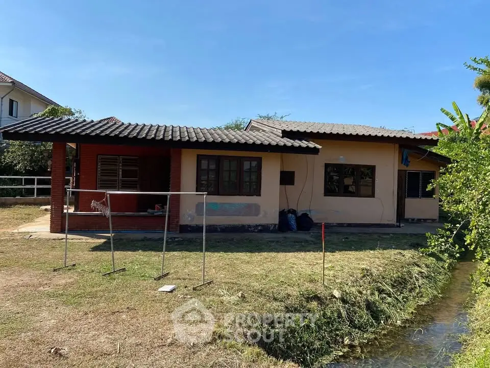 Charming single-story house with rustic design and spacious yard by a serene stream.