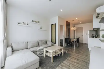 Modern living room with cozy sofa and open kitchen layout in stylish apartment.