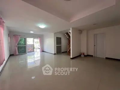 Spacious open-plan living room with large windows and staircase