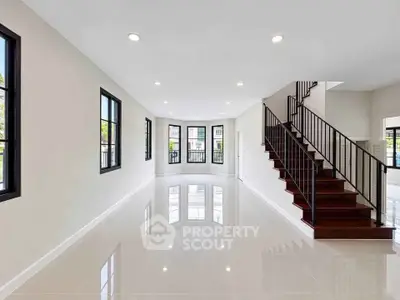 Spacious modern living room with elegant staircase and large windows