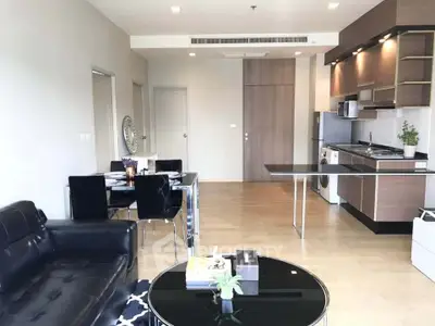 Modern open-plan living room with sleek kitchen and dining area, featuring stylish furniture and contemporary design.