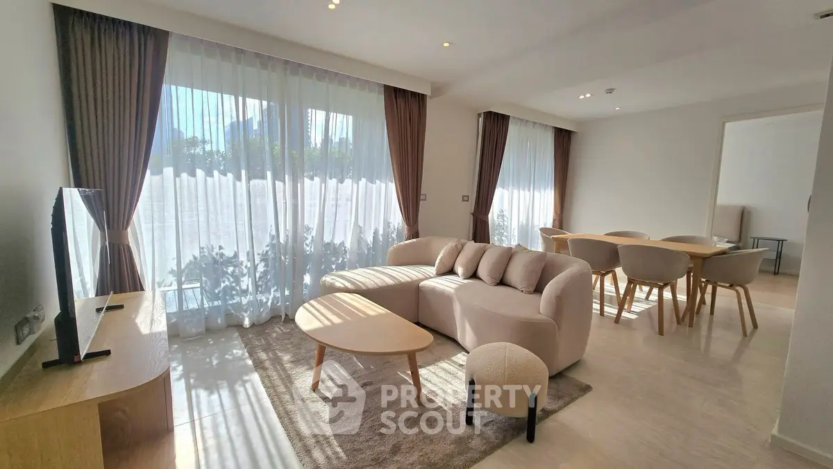 Spacious modern living room with elegant furniture and large windows offering natural light.