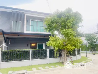 Modern two-story house with lush greenery and fenced yard