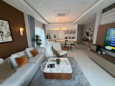 Modern living room with stylish decor and open kitchen layout, featuring cozy seating and elegant lighting.