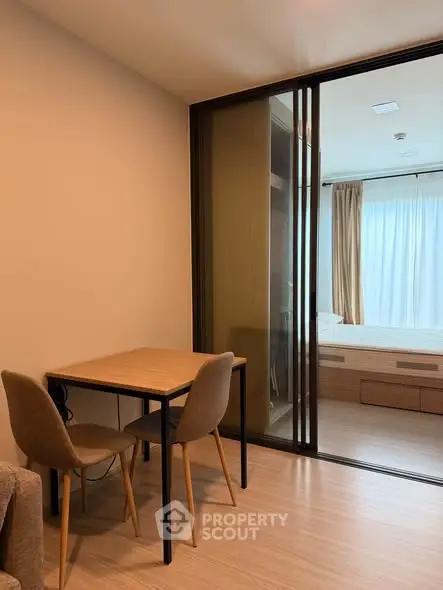 Modern apartment interior with cozy dining area and sliding glass doors leading to a bright bedroom.