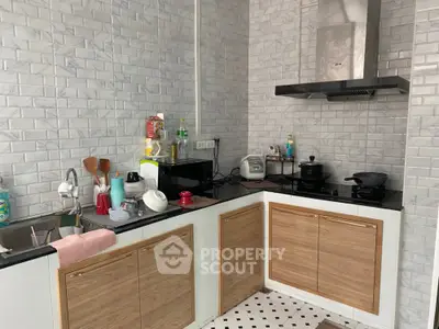 Modern kitchen with sleek cabinetry and black countertop, featuring essential appliances and stylish backsplash.