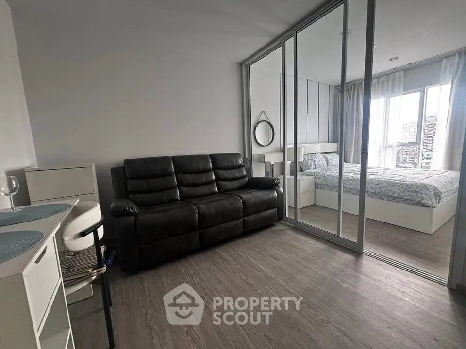 Modern apartment with sleek living room and cozy bedroom separated by glass sliding doors.