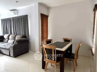 Modern living room with cozy sofa and dining area, featuring sleek furniture and natural light.