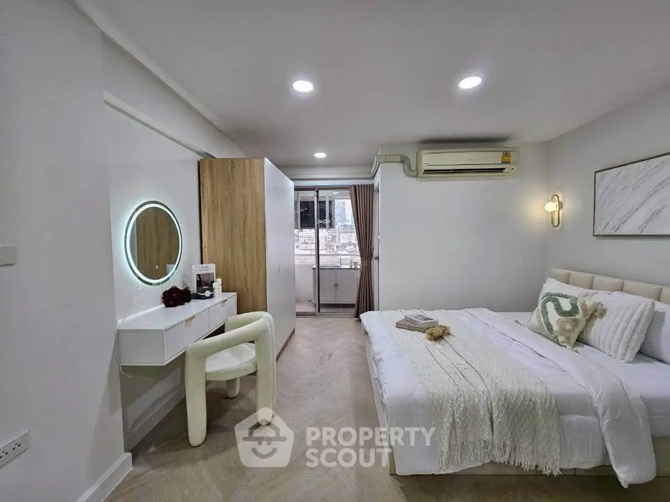 Modern bedroom with elegant decor and city view from balcony.