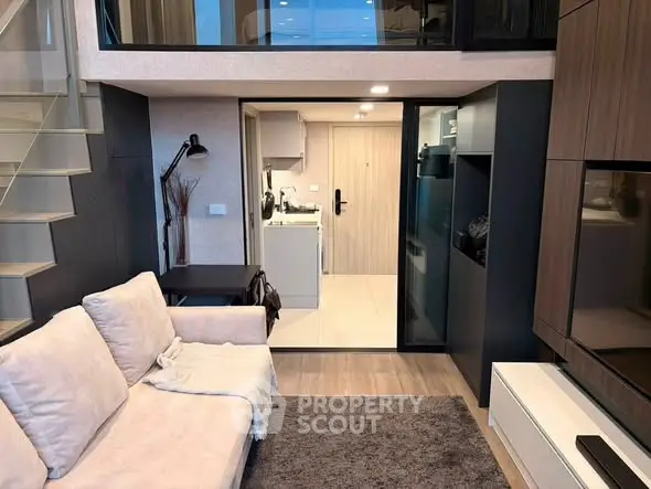 Modern living room with loft design and open kitchen layout, featuring sleek furniture and stylish decor.