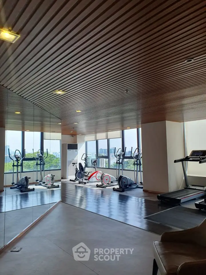 Modern gym with city view and exercise equipment in luxury building.
