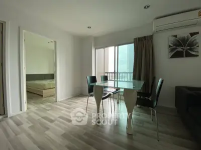 Modern apartment with open living and dining area, featuring sleek furniture and large windows.