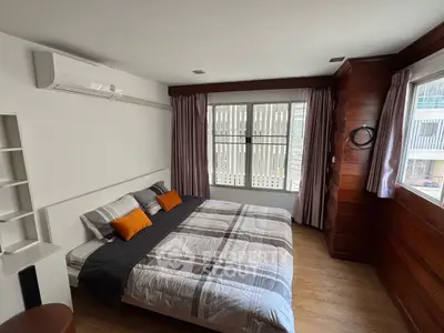 Spacious bedroom with modern decor and large windows for natural light.