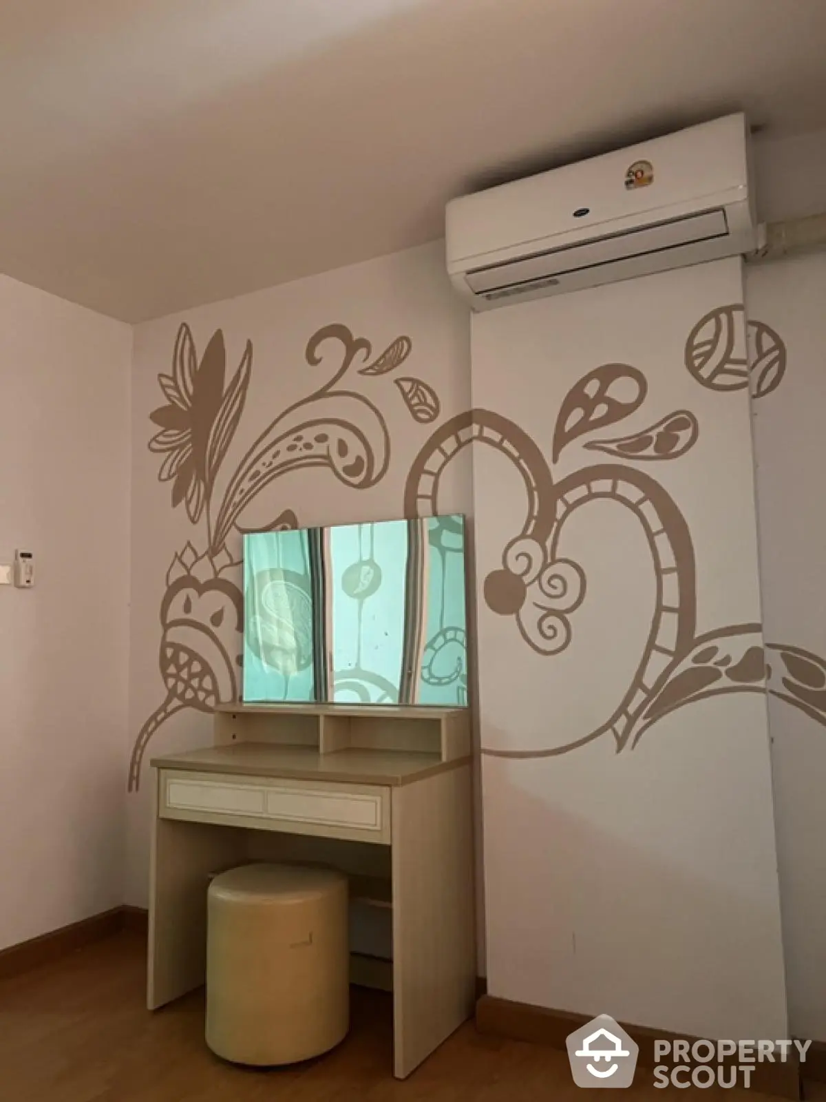 Charming bedroom corner with artistic wall design and vanity table, featuring air conditioning for comfort.