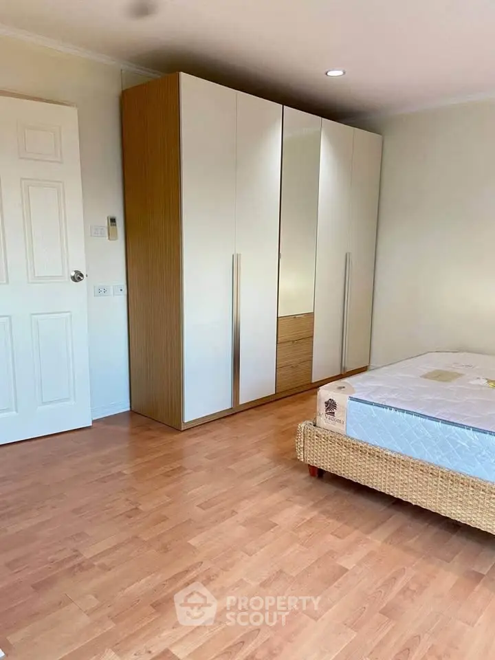 Spacious bedroom with wooden floor and modern wardrobe
