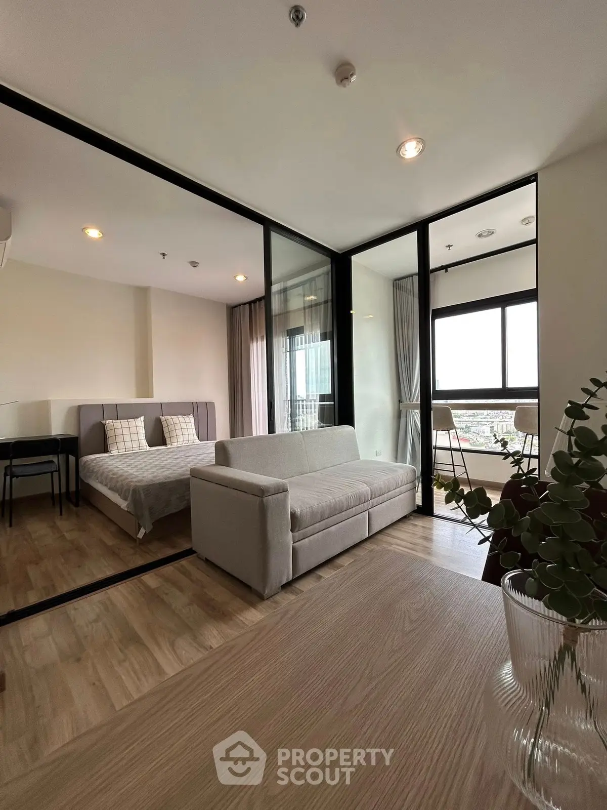 Modern apartment with glass partition, cozy living room, and bright bedroom with city view.
