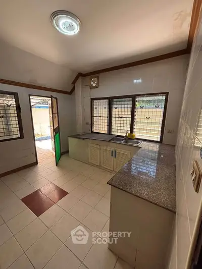 Spacious kitchen with granite countertops and large windows for natural light.