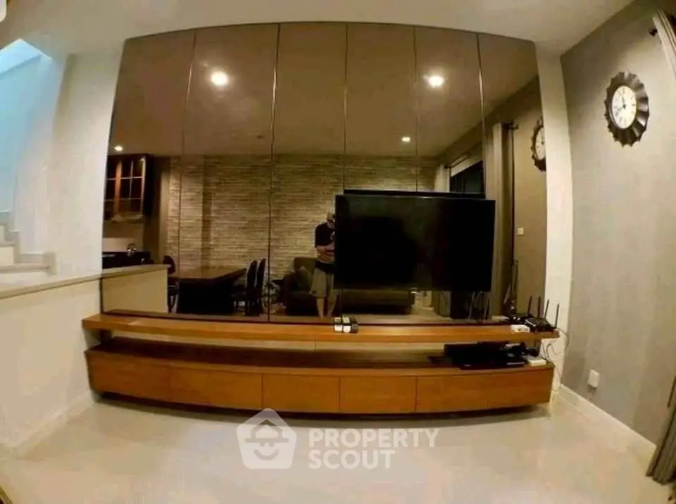 Modern living room with sleek TV unit and mirrored wall, enhancing space and style.