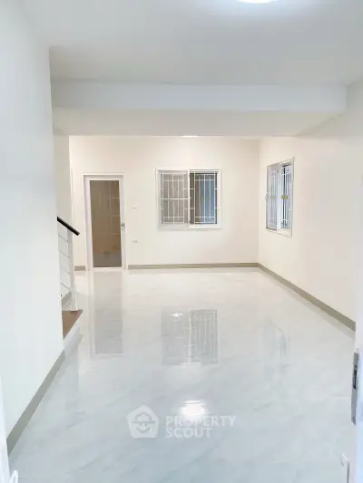 Spacious empty living room with glossy tiled floors and large windows in modern home.