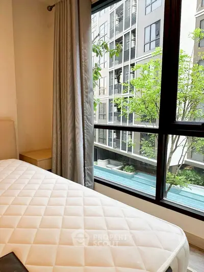 Cozy bedroom with a view of modern apartment building and lush greenery.