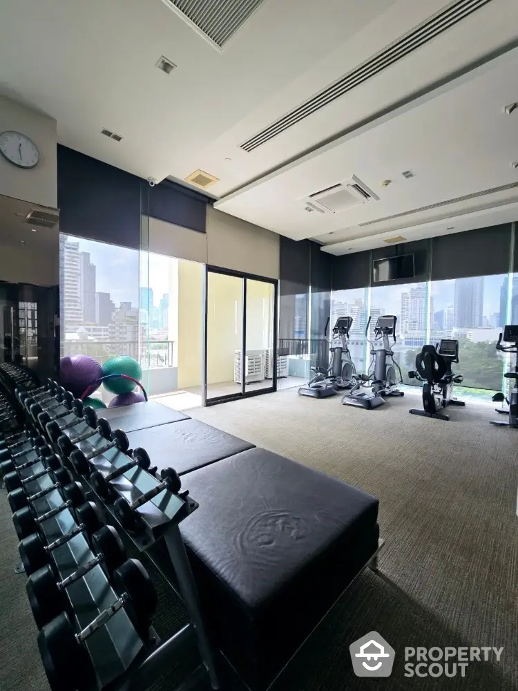 Spacious modern gym with city view and exercise equipment in luxury building