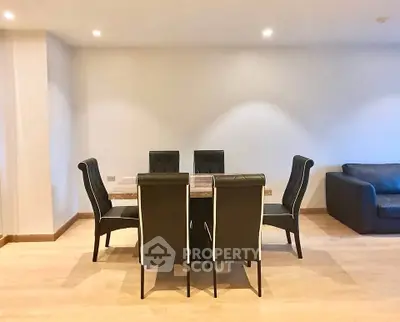 Spacious dining area with elegant black chairs and wooden flooring in modern apartment.