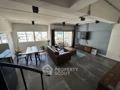 Spacious modern living room with large windows and stylish furniture in urban apartment.
