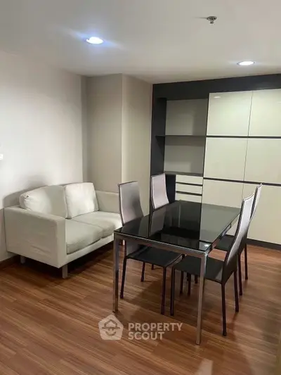Modern dining area with sleek glass table and cozy sofa in stylish apartment.