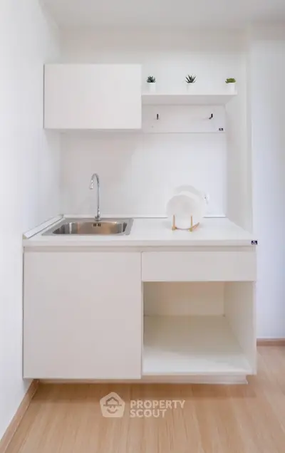 Minimalist white kitchen with sleek cabinetry and modern sink design.