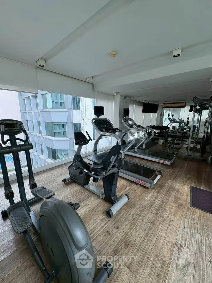 Modern gym with state-of-the-art equipment and large windows offering city views.