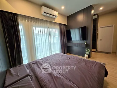 Modern bedroom with sleek black accents and natural light from large windows.