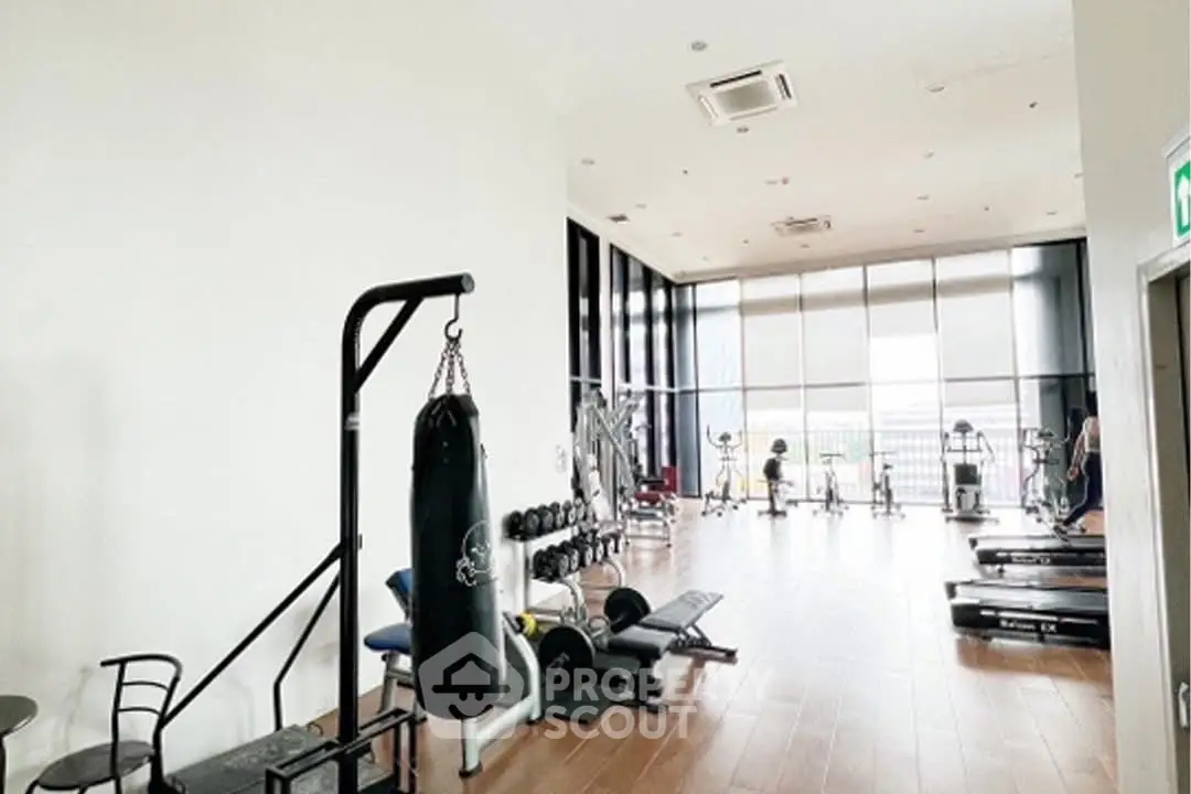 Spacious gym with modern equipment and large windows for natural light.