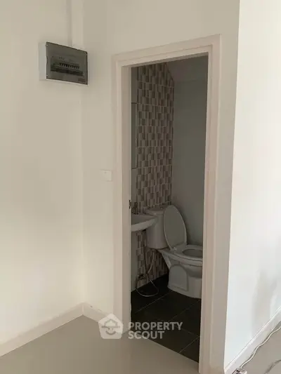 Compact bathroom with modern tiling and white fixtures in a minimalist apartment.