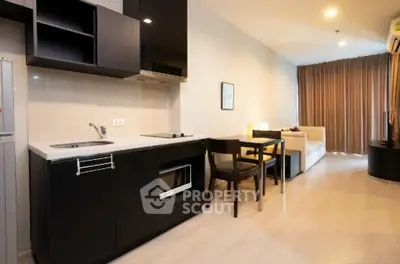 Modern open-layout kitchen and living area with sleek black cabinetry and cozy seating.