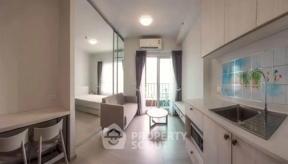 Modern open-plan living room with kitchen and balcony in a bright apartment.