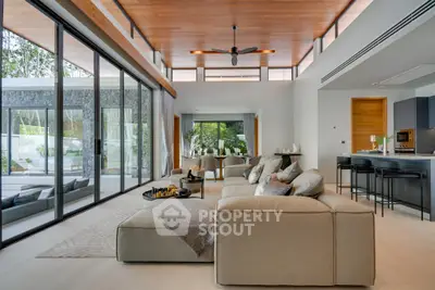 Luxurious open-plan living room with modern decor and large windows offering garden views.