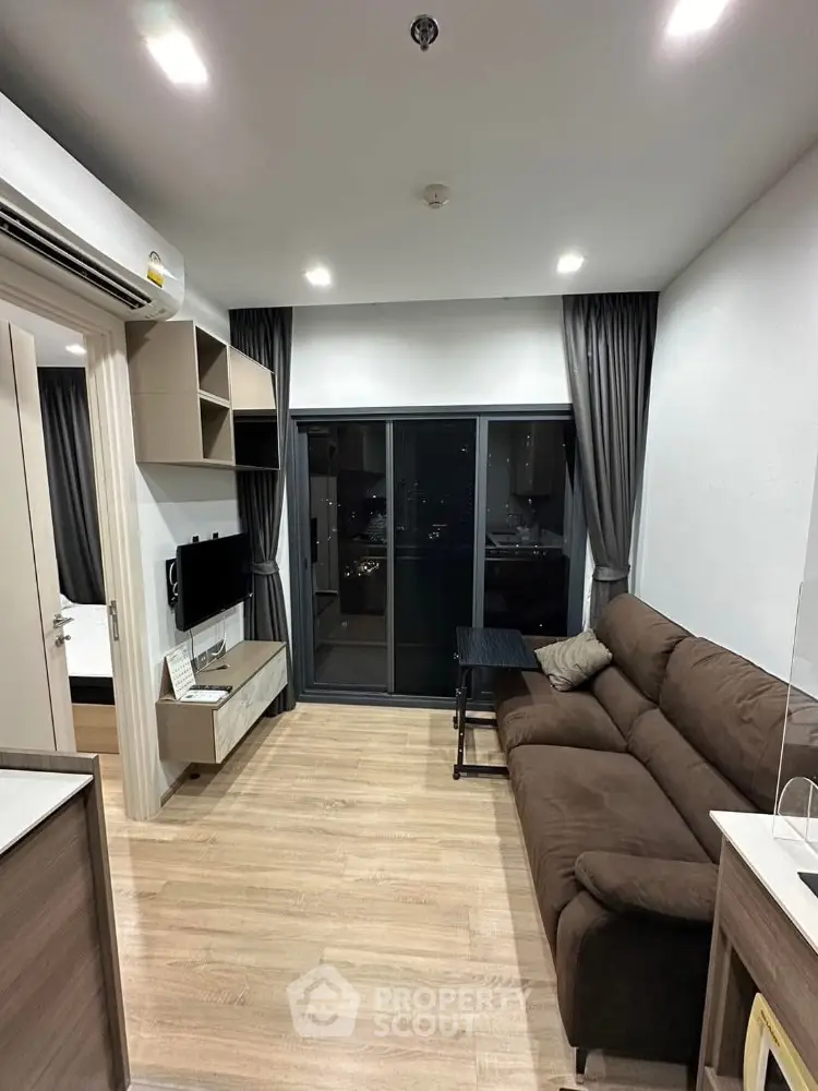 Modern living room with brown sofa and large sliding glass doors leading to balcony.