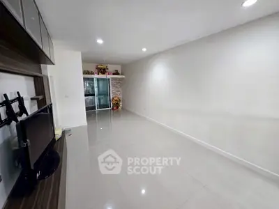 Spacious unfurnished living room with modern tile flooring and built-in TV stand, ready for customization.