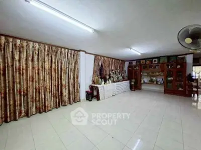 Spacious living room with tiled floor and decorative curtains, ideal for family gatherings.
