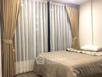 Cozy bedroom with elegant curtains and comfortable bedding in modern apartment.