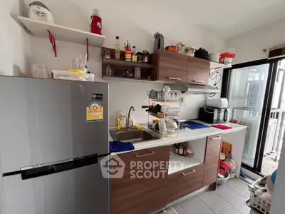 Modern compact kitchen with wooden cabinets and stainless steel fridge in urban apartment.