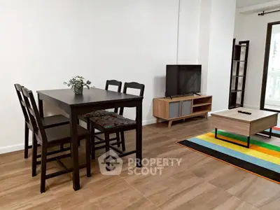 Modern living room with dining set and TV unit, featuring wooden flooring and colorful rug.
