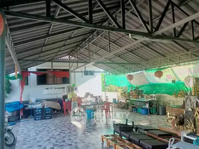 Spacious covered outdoor area with tiled flooring and metal roof, ideal for gatherings or storage.