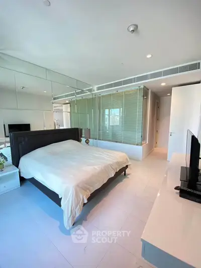 Luxurious modern bedroom with mirrored wall and sleek furnishings